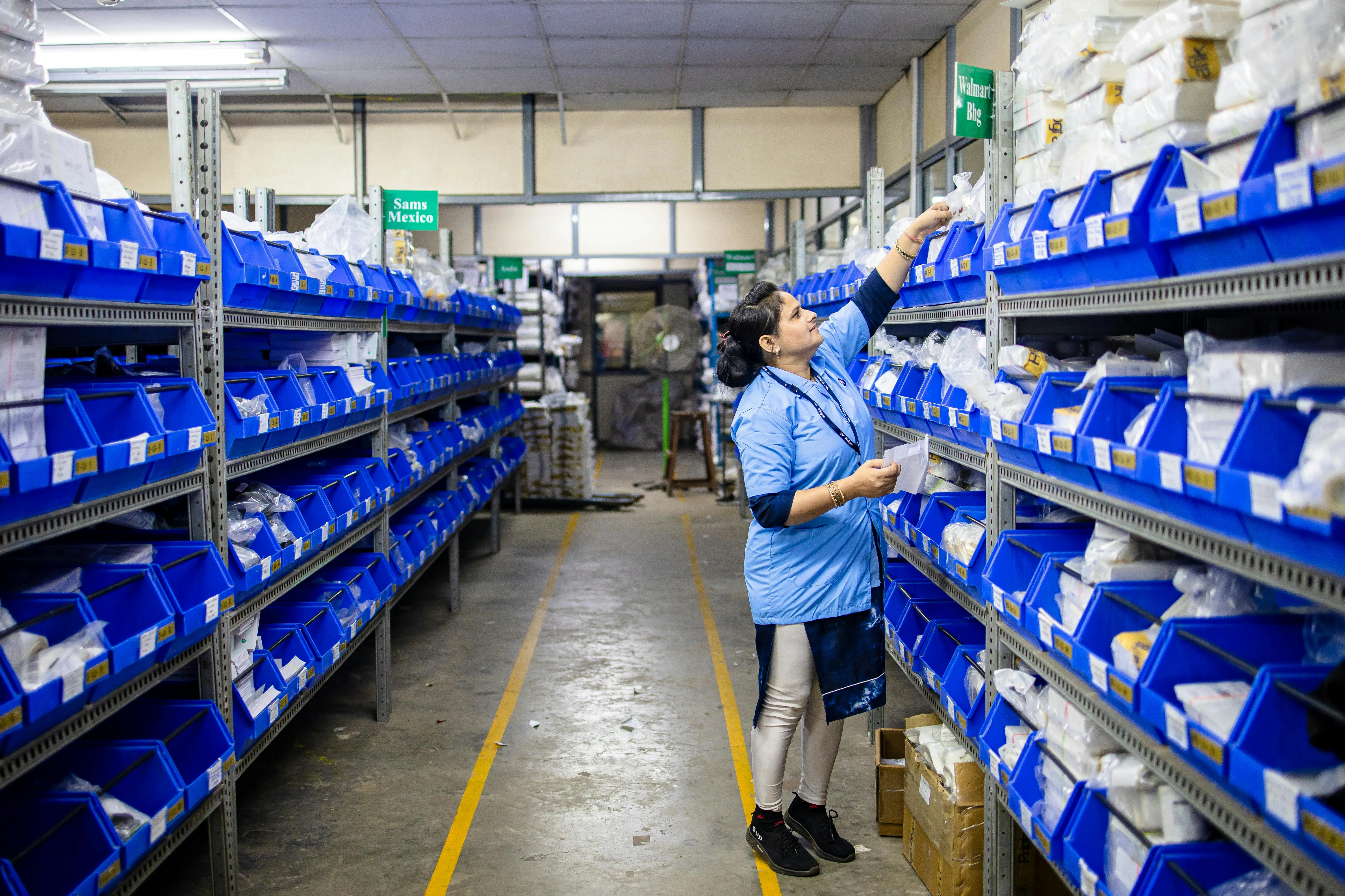Warehouse worker organizing inventory shelves with cardboard boxes for ecommerce order fulfillment