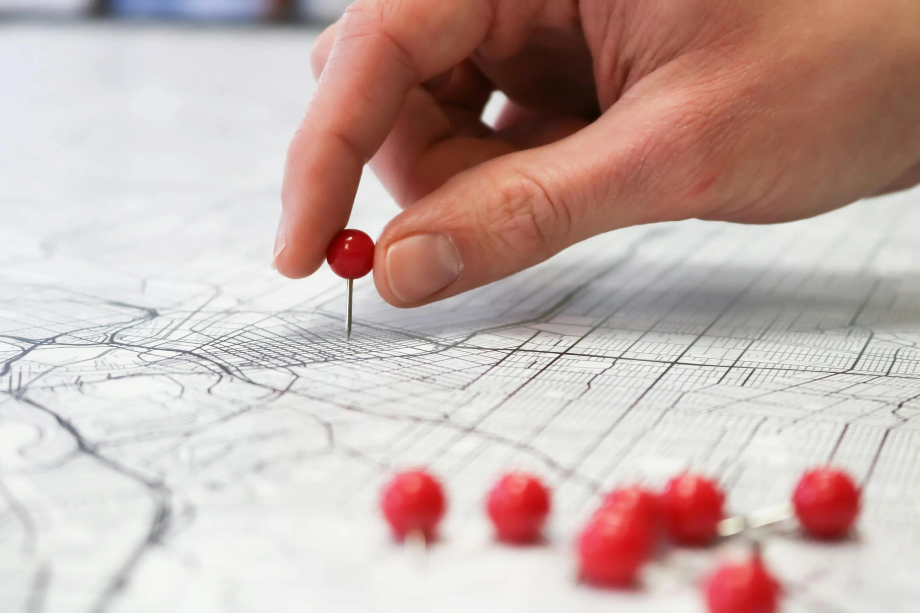 Hand placing a red pin on a map — QuickBooks Online location tracking for Shopify merchants