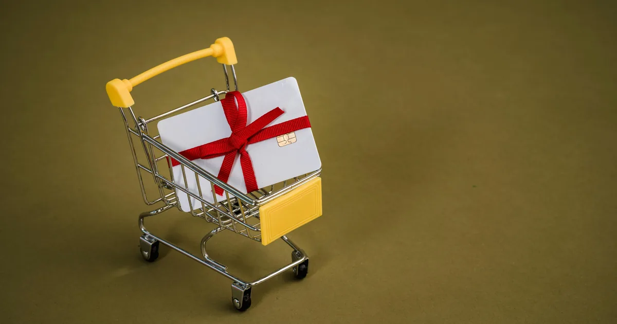 Gift card with red bow in a mini shopping cart — Shopify gift card accounting in QuickBooks Online with WeIntegrate