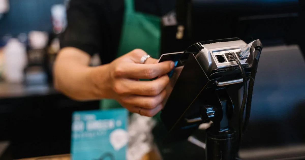 Barista processing a credit card payment on a point-of-sale terminal — Shopify payment processing fees and QuickBooks Online expense tracking