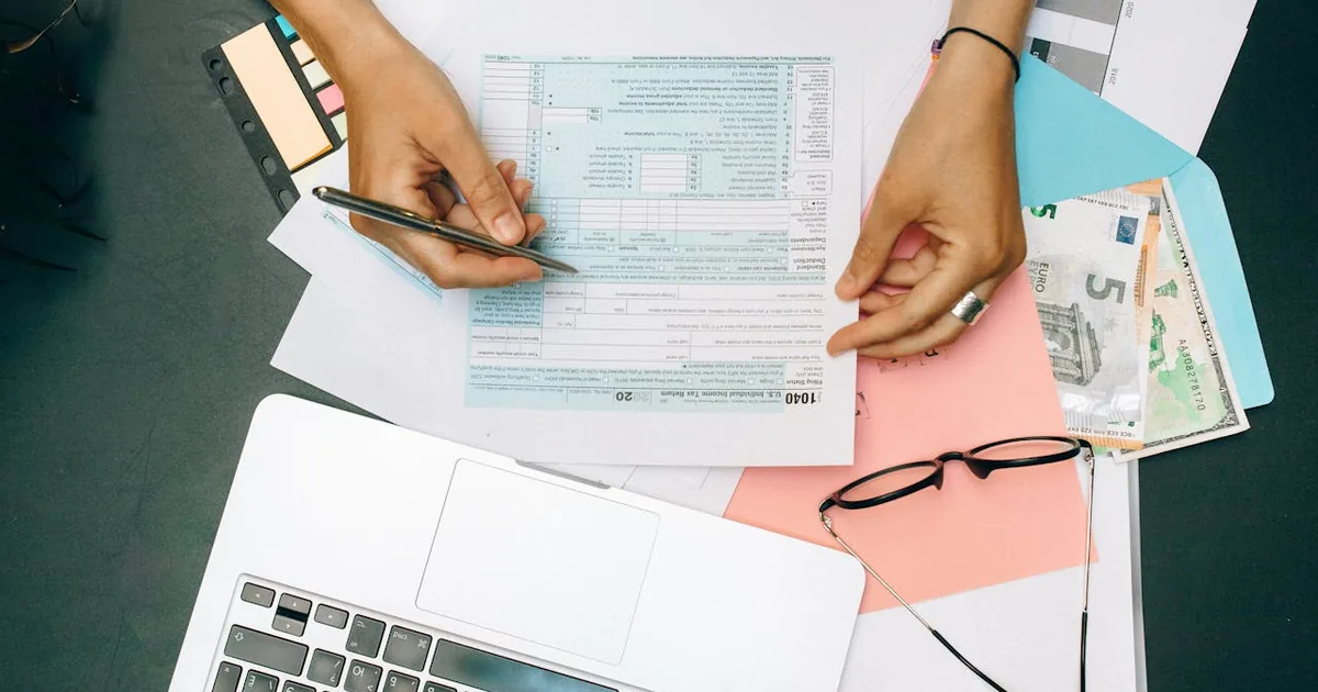 Small business owner reviewing shipping costs on laptop at a home office desk — Shopify shipping label fees recorded as QuickBooks Online expense
